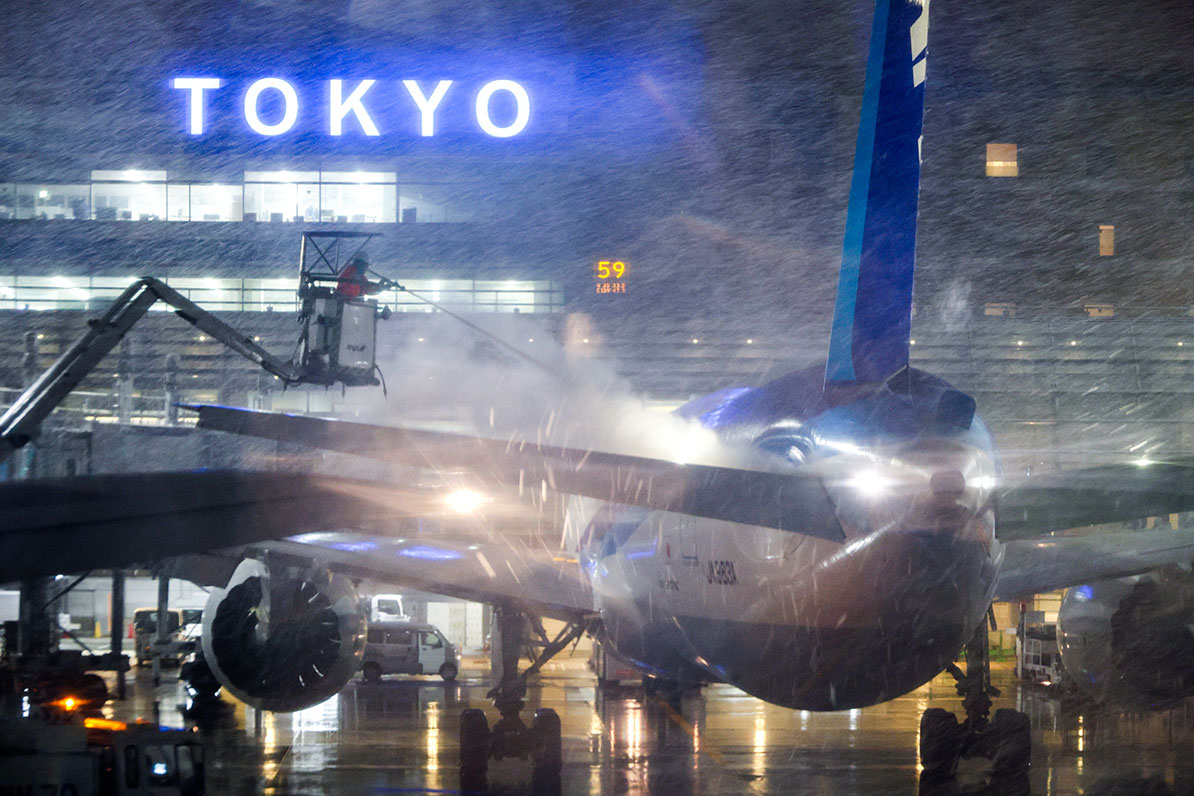 寒空の下で守られる翼 — 雪の羽田空港での除氷作業